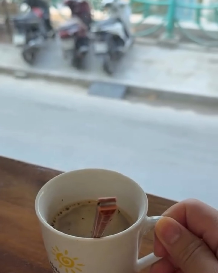 Tách cà phê đặt trên mặt bàn gỗ sát cửa sổ nhìn ra phố