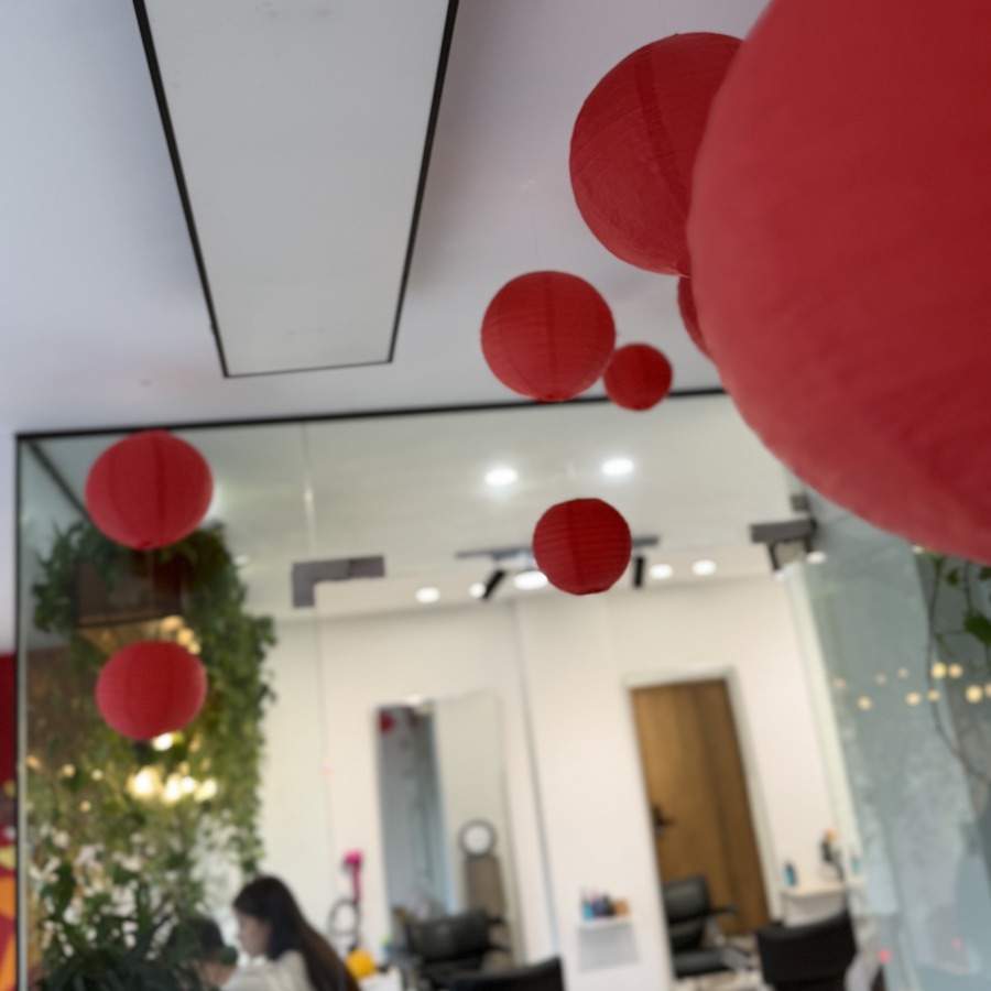 Lồng đèn đỏ treo trước gương và mảng cây xanh trong salon